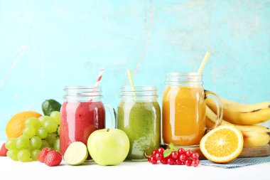 Cam kavanozlarda taze meyve ve sebzeler ahşap arka planda.