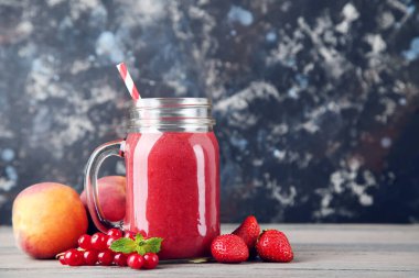 Siyah arkaplanda böğürtlenli cam kavanozda kırmızı smoothie.