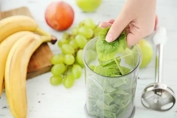 Woman making healthy spinach smoothie in blender