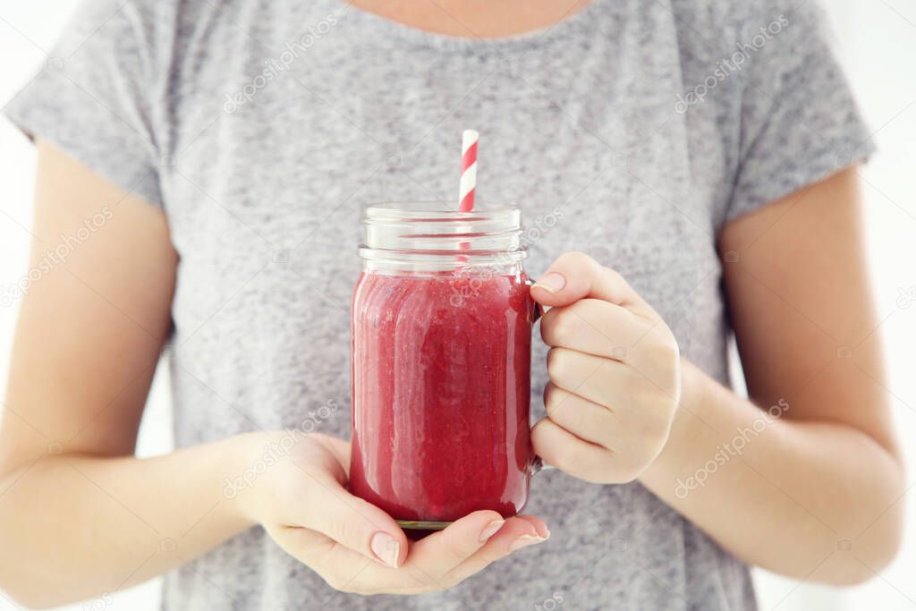 Woman holding in hands glass jar with red smoothie