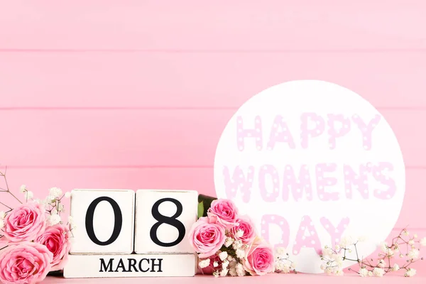 花やテキストの花束とカレンダーキューブピンクの木製の背景に幸せな女性の日 — ストック写真