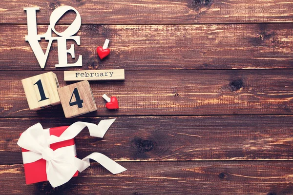ギフトボックスと単語と2月のブロックカレンダー茶色の木製のテーブルの上の愛 — ストック写真