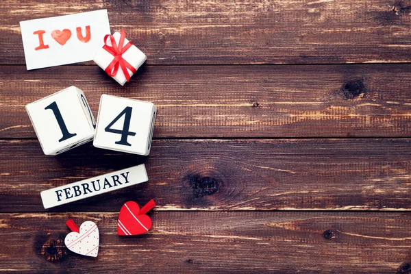 茶色の木製のテーブルの上の心とギフトボックスと2月のブロックカレンダー — ストック写真