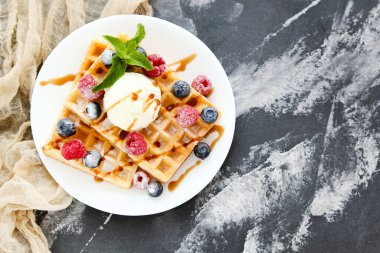 Taze böğürtlenli lezzetli waffle ve gri arka planda dondurma.