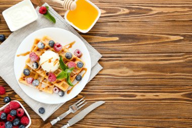 Taze böğürtlenli lezzetli waffle ve kahverengi ahşap arka planda dondurma.