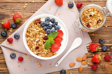 Taze böğürtlenli lezzetli granola ve kahverengi ahşap arka planda kaşık.