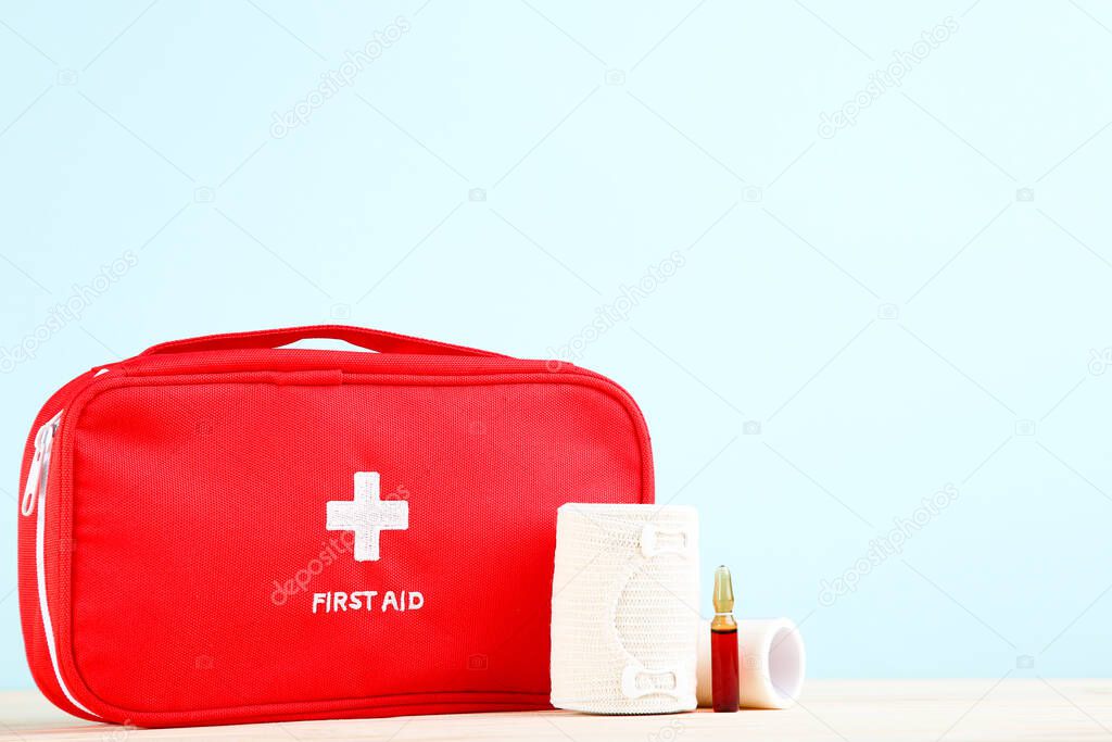 First aid kit with medical supplies on mint background