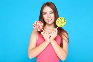 Mavi arka planda lolipopları olan güzel kız.
