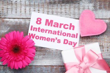 Gerbera çiçeği, kumaş kalp, hediye kutusu ve kart. Üzerinde 8 Mart Uluslararası Kadınlar Günü yazılı.