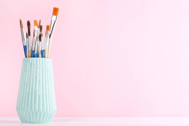 Pembe arka planda vazoda sanatsal fırçalar