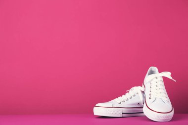 Pembe arka planda bir çift spor ayakkabı.