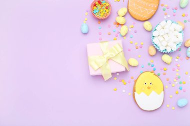 Marşmelovlu Paskalya zencefilli kurabiyeleri, hediye kutusu ve mor arka planda süslemeler.