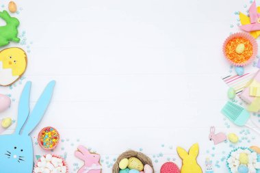 Paskalya konsepti. Renkli yumurtalı kurabiyeler, lokum ve beyaz ahşap masaya serpiştirilmiş şekerlemeler.