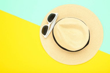 Renkli kağıt arka planda yaz hasır şapkası ve güneş gözlüğü