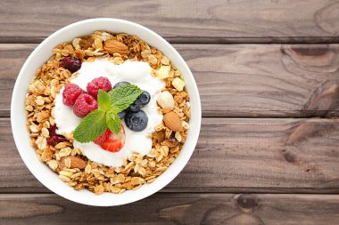 Kahverengi ahşap arka planda taze böğürtlenli lezzetli granola.