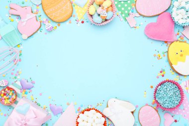 Renkli yumurtalı Paskalya zencefilli kurabiyeleri, hediye kutusu ve mavi arka planda süslemeler.