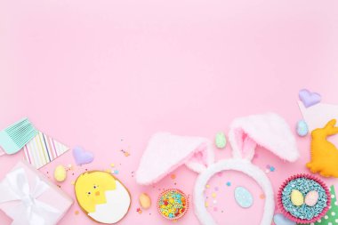 Paskalya zencefilli kurabiyeler hediye paketi, tavşan kulakları ve pembe arka planda serpiştirmeler.