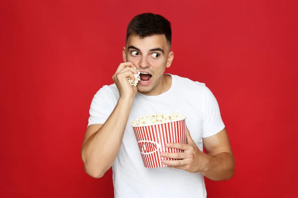 Junger Mann Mit Eimer Popcorn Auf Rotem Hintergrund — Stockfoto