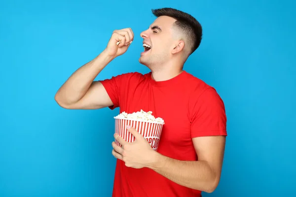 Junger Mann Isst Popcorn Auf Blauem Hintergrund — Stockfoto