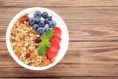 Kahverengi ahşap arka planda taze böğürtlenli lezzetli granola.