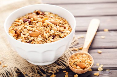 Lezzetli granola kasede ve kaşık kahverengi ahşap arka planda