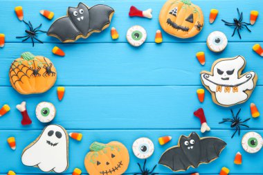 Cadılar Bayramı zencefilli kurabiyeler ve mavi ahşap masada örümcekler.