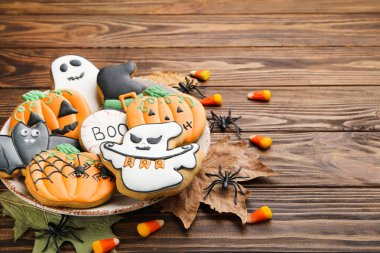 Kahverengi ahşap masada şekerli zencefilli kurabiyeler, örümcekler ve kuru yapraklar.