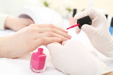 Manikürcü, kuaförde müşteri için manikür yapıyor.