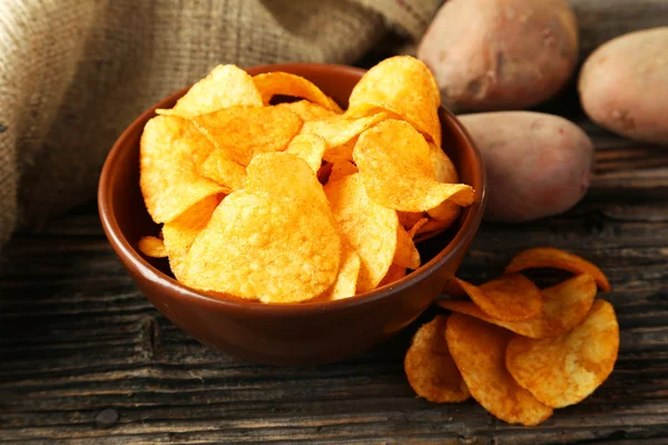 Chips in bowl and potatoes — Stock Photo, Image