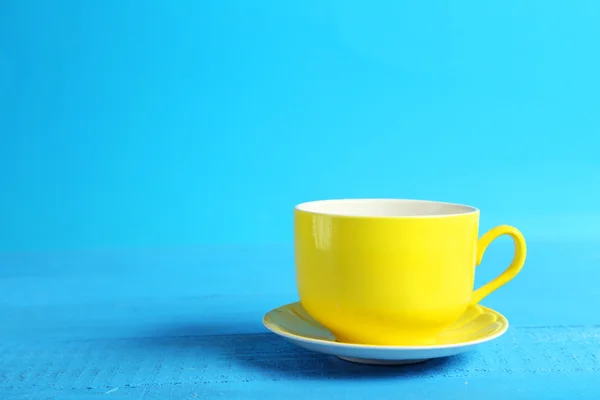 Copo amarelo isolado em azul — Fotografia de Stock