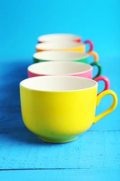 Colorful cups isolated on blue — Stock Photo, Image