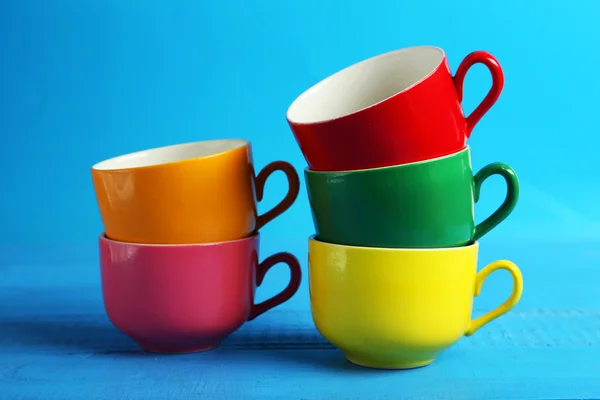 Colorful cups isolated on blue — Stock Photo, Image