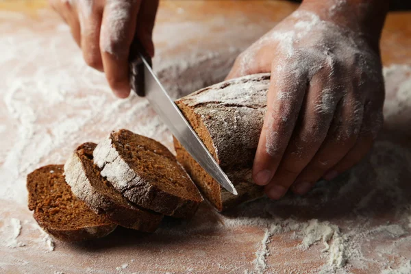 Mãos masculinas cortando pão — Fotografia de Stock