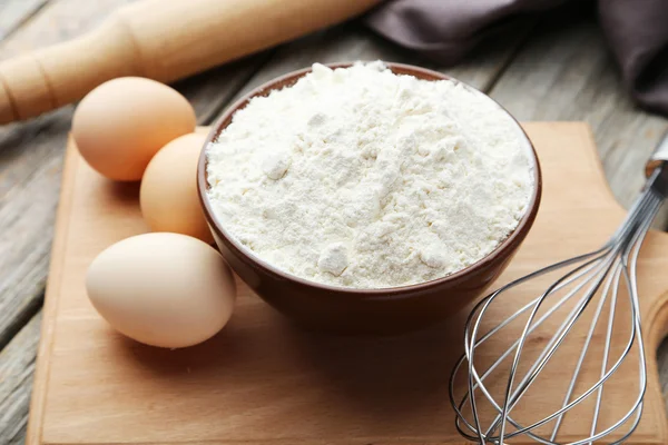 Cuenco de harina de trigo con huevos y batidor — Foto de Stock