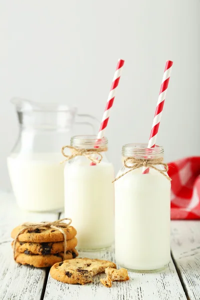Bottles of milk with striped straws and cookies — Stock Photo, Image