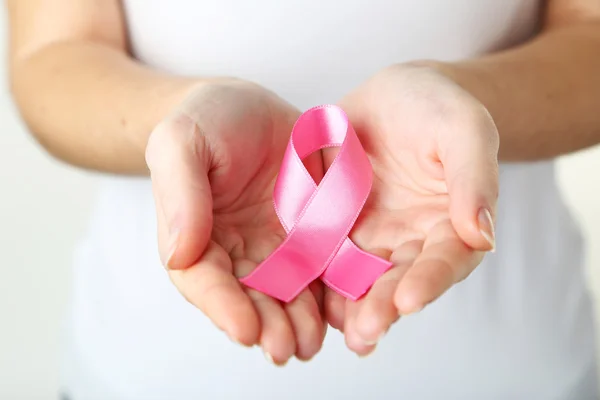 Mãos femininas segurando fita rosa — Fotografia de Stock