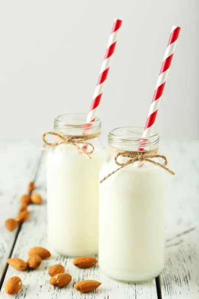 Dua botol susu dengan sedotan bergaris dan almond — Stok Foto