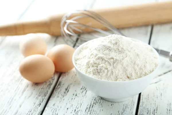 Cuenco de harina de trigo con huevos y batidor — Foto de Stock