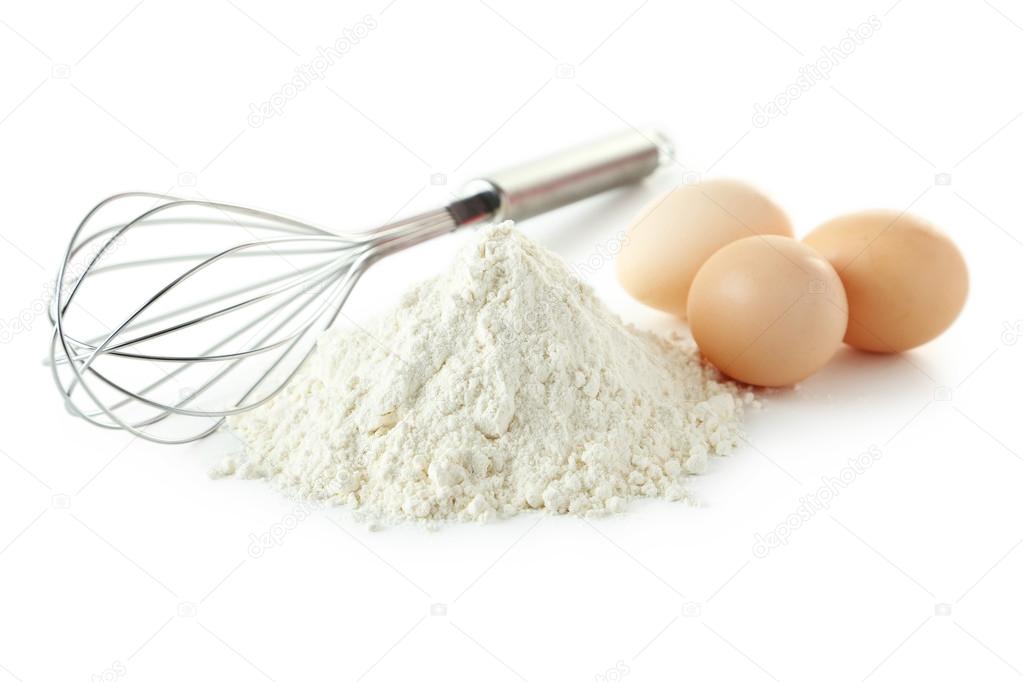 Heap of wheat flour with eggs and whisk