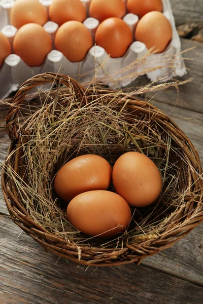 Яйца в корзине на деревянном фоне — стоковое фото