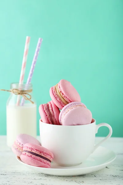 French macarons in cup on white wooden background — Stock Photo, Image