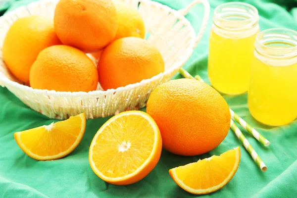 Orange juice and oranges in basket — Stock Photo, Image