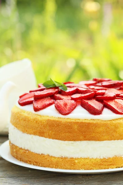 Zoete cake met aardbeien op de plaat op witte houten achtergrond — Stockfoto