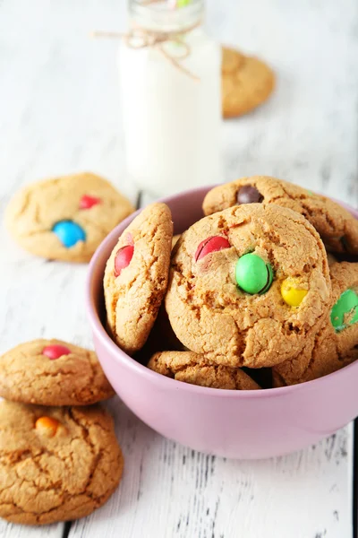 Cookies med färgglada godis i skål på vit trä bakgrund — Stockfoto