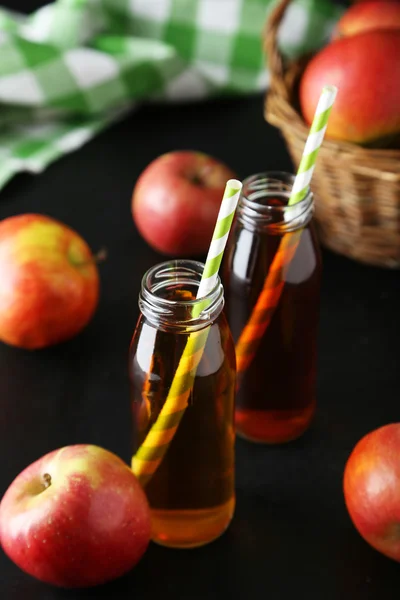 Пляшки яблучного соку з яблуками на чорному тлі — стокове фото