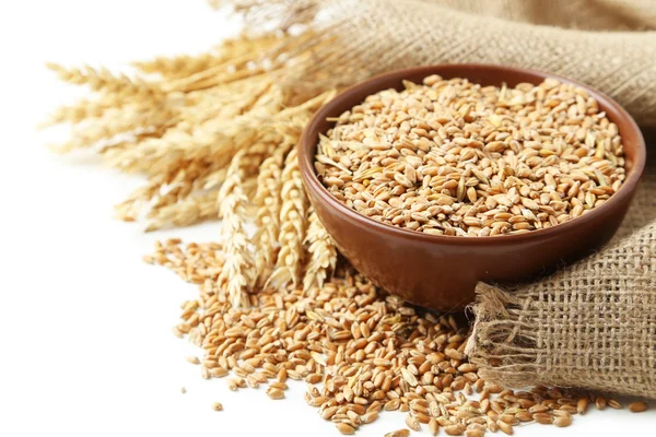 Уши пшеницы и миска зерна пшеницы на белом фоне — стоковое фото