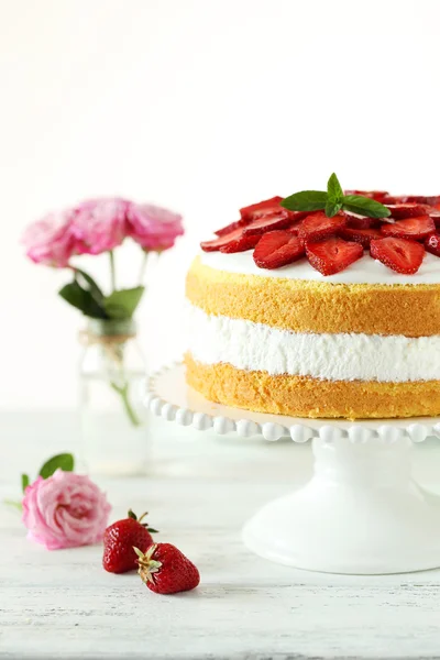 Zoete cake met aardbeien op de plaat op witte houten achtergrond — Stockfoto