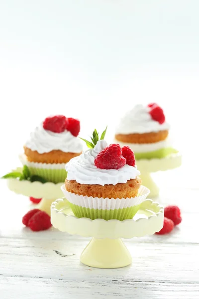 Hallon cupcakes på kakan stå på vit trä bakgrund — Stockfoto