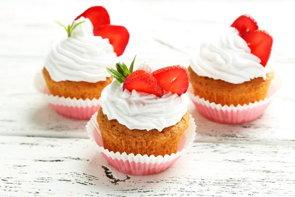 Smakelijke cupcake met aardbeien op witte houten achtergrond — Stockfoto