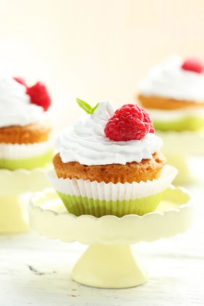 Cupcakes de framboesa no carrinho de bolo no fundo de madeira branco — Fotografia de Stock